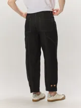 Pantalón de lino color blanco crudo, de corte barrel, con bolsillos laterales y costuras pespunteadas a contratono.