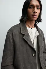 Blazer relaxed fit de piel con acabado ante, color gris oscuro. Cuello con solapas de muesca, manga larga, bolsillo de plastrón con solapa en el pecho y dos bolsillos de plastrón en la cadera. Cierre frontal de botonadura con botones claros.