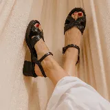 Sandalias de taco ancho color negro con textura efecto reptil, diseño de tiras cruzadas en el empeine y tira ajustable con hebilla en el tobillo.