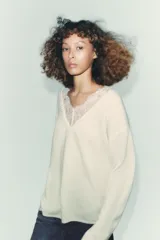 Jersey negro de manga larga con escote en V adornado con encaje negro.