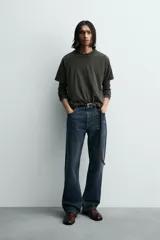 Camiseta relaxed fit color gris oscuro, confeccionada en tejido ligero de algodón con elasticidad. Presenta cuello redondo y manga ranglán corta.