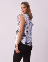 Blusa de algodón estampada con flores en tonos celeste y azul, cuello mao, escote en V, abertura frontal con botones y volados en las sisas.