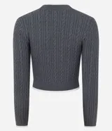 Sweater cropped de punto gris con diseño trenzado, cuello redondo, puños y ruedo con ribetes blancos. Presenta un aplique bordado en el pecho con diseño de osito deportista.