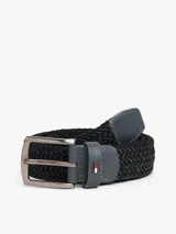 Cinturón trenzado elástico de color negro, con hebilla metálica cuadrada de acabado oscuro y trabilla de cuero sintético gris con el logo de Tommy Hilfiger.