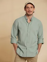 Camisa de manga larga color verde claro, con cuello clásico y cierre frontal con botones.