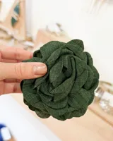 Broche de pelo con forma de flor de tela color verde oscuro.
