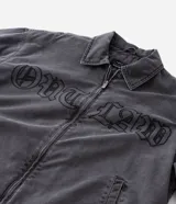 Chaqueta de denim color gris con acabado estonado, cierre frontal con cremallera, cuello camisero y manga larga. Presenta un estampado con la palabra 'OUTLAW' en tipografía gótica en el pecho y un bolsillo con cierre en la manga izquierda.
