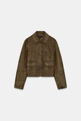 Cazadora corta color marrón de efecto ante, con cuello solapa, manga larga y bolsillos de plastrón con solapa en el delantero. Cierre frontal con botones.