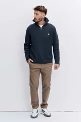 Sweater de punto acanalado en color azul marino, con cuello alto y cierre frontal parcial. Presenta un pequeño bordado en el pecho y mangas largas.