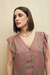 Blusa estampada con motivos de hojas en tonos beige y negro, con escote en V, botones al frente y volados en los hombros.