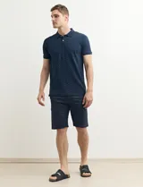 Remera polo azul marino con estampado de pequeños puntos blancos, cuello clásico con tres botones y mangas cortas.