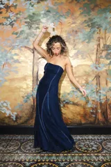 Vestido largo strapless de encaje negro con transparencias y espalda descubierta con tiras cruzadas, de corte entallado y falda de caída suelta.