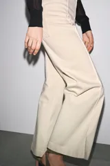 Jeans de tiro alto, pierna ancha y largo al tobillo, en denim celeste claro con efecto lavado. Presenta costura marcada en el centro de cada pierna y cierre frontal con cremallera y botón.