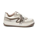 Championes deportivos de diseño urbano, combinando tonos blanco, beige y marrón. Presentan una silueta de plataforma con suela de goma, cordones blancos y un detalle decorativo de dijes metálicos colgantes en el empeine. El lateral incluye un diseño curvo distintivo y el logo VM grabado en la suela.