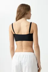 Top de bikini negro con tirantes finos y bordado de flores blancas.