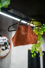 Top deportivo marrón con cuello halter y logo Hermod estampado en blanco.