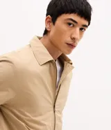 Campera bomber masculina de sarga color beige, con cuello inglés, cierre frontal de cremallera, bolsillos y elásticos en puños y cintura.