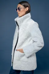 Campera reversible de cuero ovino, color azul marino, con interior de piel sintética blanca. Presenta cuello alto, cierre frontal y bolsillos frontales aplicados.