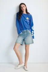 Remera oversize de manga larga color azul, con efecto lavado, cuello redondo y detalle de estampación inspirada en Henri Matisse con una estrella amarilla en el pecho y formas abstractas blancas en la manga.