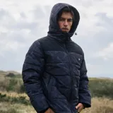 Campera parka Maui and Sons con estampado camuflado en tonos azules y negros. Tiene capucha fija con forro interior, cierre frontal con tapeta y broches metálicos, bolsillos frontales con cierre y tapeta, puños interiores rib y acolchado liviano.