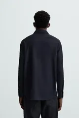 Camisa blanca de manga larga con cuello italiano y cierre frontal de botonadura. Corte regular fit.