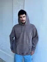 Buzo canguro marrón con capucha y cordones, de corte amplio y estilo urbano.