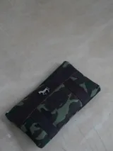 Sobre tipo cartuchera de lona con estampado de camuflaje y terminaciones en cuero marrón.