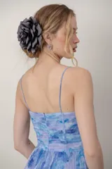 Vestido midi de tul plisado con estampado floral en tonos celestes y violetas, tirantes finos y detalle drapeado tipo corsé en el cuerpo.