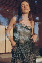 Top de tirantes finos con estampado de lunares, confeccionado en tejido semitransparente. Presenta detalles de encaje en el escote y un bajo asimétrico con volantes.