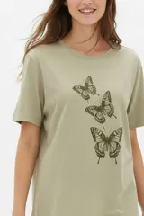 Remera de manga corta color blanco, de corte holgado con cuello redondo a la base y estampado frontal en tono bordó de un gato y un ovni en un paisaje desértico.