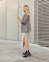 Botas de cuero negras con punta cuadrada, tacón ancho y detalles de textura en relieve en la parte superior.