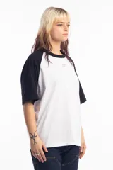Remera de corte oversize con diseño tipo ranglan, que combina cuerpo blanco con mangas y cuello en color negro. Presenta un pequeño logo bordado en el centro del pecho.