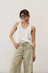 Pantalón de jean de corte wide leg, tiro medio y lavado claro con efecto desgastado. Presenta diseño de múltiples paneles con costuras pespunteadas verticales y roturas en ambas piernas.