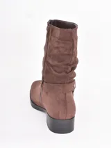 Bota corta de gamuza color marrón con efecto arrugado en la caña, cierre lateral y detalle de tira con hebilla metálica circular en el tobillo.