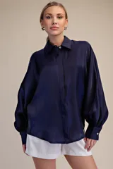 Blusa de satén azul marino con cuello camisero y mangas largas voluminosas con puños abotonados.