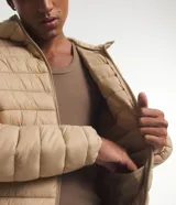 Campera ultraligera gris con capucha, cierre de cremallera, bolsillos con cremallera y diseño acolchado.