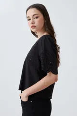 Blusa negra de broderie con escote en V y lazos para atar en el frente. Tiene mangas cortas con terminación de puntilla. 