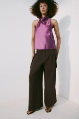 Top halter confeccionado en tejido satinado de color lila, con escote fluido y hombros descubiertos. Presenta cierre en la espalda con botón oculto.