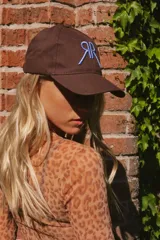 Gorra marrón de algodón con logo bordado en celeste en el frente y ganchito ajustable en la parte trasera.