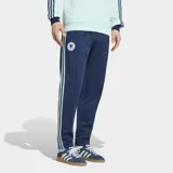 Pantalón deportivo Adidas de la colección Originals, inspirado en la selección de fútbol de Alemania. Es de color azul marino con las icónicas tres tiras laterales en color celeste. Presenta el escudo de la selección alemana en el muslo derecho y un corte clásico con cintura elástica y cordón de ajuste.