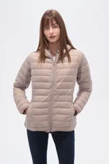 Campera acolchada tipo puffer, color beige claro, con capucha y cierre frontal. Presenta costuras horizontales y un calce entallado.
