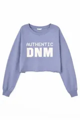 Remera crop top de manga larga color lila, con cuello redondo y estampa frontal con el texto AUTHENTIC DNM en color blanco.