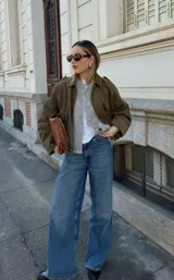 Chaqueta tipo bomber de gamuza en color verde oliva, con cuello camisero, cierre frontal oculto y diseño de corte holgado con hombros caídos.