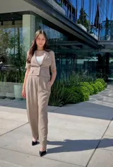 Pantalón de vestir color beige, de corte recto y tiro alto, con bolsillos laterales y cierre frontal.