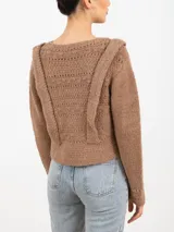 Sweater tejido color rosa con cuello redondo y mangas largas. Presenta apliques de tablas en los hombros y en el frente.
