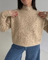 Sweater de punto color beige con cuello alto, manga larga y diseño bordado al tono con motivos florales en el frente y las mangas.