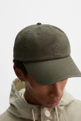 Gorra de algodón color verde oscuro, con efecto lavado y visera curva. Presenta un bordado discreto en el frente.