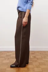 Pantalon de corte recto y pierna ancha, confeccionado en tejido tipo denim oscuro. Presenta tiro alto, cintura con cierre frontal y bolsillos laterales funcionales.