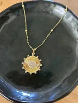 Collar dorado con cadena de eslabones y dije circular con corazón central de strass.