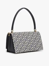 Cartera bandolera Tommy Hilfiger de diseño estructurado, confeccionada en jacquard con monogramas TH en tonos azul marino y beige, combinada con detalles en cuero sintético negro. Cuenta con solapa frontal, cierre metálico con logo, asa superior y correa extraíble.